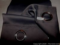 Close-up image showing part of the black drape’s fabric and two large metal grommets at the top edge.