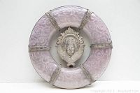 Front view showing the full circular glass with pink rose pattern and central metal angel face with wings and halo.