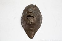 Front view of bronze mask-shaped wall hanging on white background