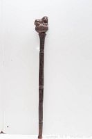 Full length image showing the 23 inch ceremonial stick in dark wood with a carved lion head on top.
