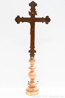 Front view of the bronze cross statue showing its full height and composite base.