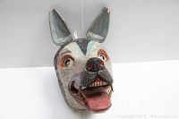 Front and slightly angled view showing the painted dog's head with open mouth and visible teeth. The dog's face is detailed with white, grey, red and black paint. Visible chip on one ear is shown.