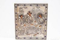 Front view of the embossed metal wall hanging showing three angelic figures sitting at a table with glass stones on halos and border.