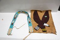 Photo showing both the beaded belt and buckskin wall hanging with eagle motif laid flat on a white surface.
