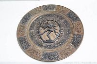 Full view of round metal embossed plate with Buddha and Thai relief designs