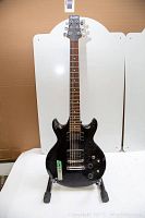Full body view of black Ibanez electric guitar showing two humbucker pickups, rosewood fretboard, and some wear on the finish.