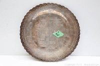 Front view of round sterling silver plate with scalloped rim and engraved Egyptian figures with hieroglyphics