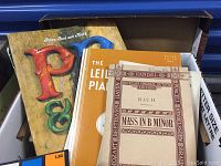 Box of books with covers visible: 'P & F', 'The Leibling Piano', and 'Mass in B Minor' by Bach.