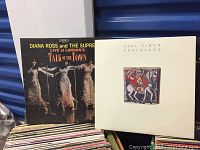 Front row shows Diana Ross & The Supremes ‘Talk of the Town’ LP next to Paul Simon ‘Graceland’ with boxes of records behind