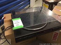 Full view of Dual CS 530 turntable with dust cover down showing the platter and tonearm on a cardboard box.