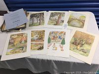 Top down view of eight colorful Winnie The Pooh art prints spread out on a table showing various characters and scenes from the classic children's stories.