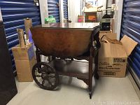 Side view of wooden tea cart showing large decorative wheels and lower shelf
