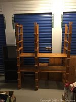Overall view of the natural wood adjustable shelving unit standing vertically with several shelves and four support rails.