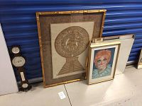 Lot items against blue storage background: large framed Mexican goddess print, clown painting, mirror, and barometer leaning on wall.