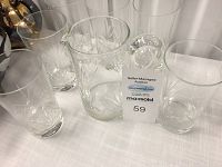 Photo showing six clear drinking glasses and one water jug on a table with auction lot number tag