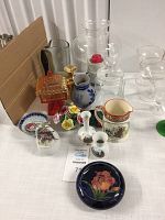 Overall view of the collection of vases, ceramic figurines, jugs, and glassware on the table.