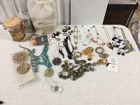 Wide view of assorted necklaces, earrings, and buttons laid out on table