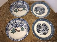 Four pie plates arranged on carpet: two with Folk Craft Cabin in the Snow design, two with Royal China Currier and Ives print.