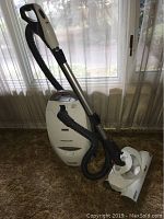 Full side view of Kenmore Progressive canister vacuum cleaner, showing wand, hose, and vacuum body on carpet.