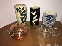 Three ceramic vases, copper pot incense holder, and clear glass teapot displayed on wooden surface.
