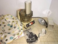 General Electric Food Processor with floral fabric cover and user manual on counter