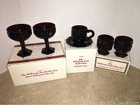 Five-piece set of Avon Cape Cod Collection glassware including two saucer champagne glasses, one cup and saucer set, and two footed glasses, all boxed.
