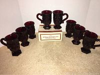 Eight Avon Cape Cod pedestal mugs arranged on carpet; two stacked on original box, six placed around it