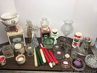 Wide shot of various candles and votive holders including holiday themes and plain glass holders.