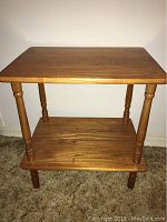 Full view of small wood side table showing two-tier design, turned legs, and wood grain finish.