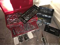 Overall view of open red Craftsman tool chest showing wrenches, sockets, ratchets, and hand tools scattered in and around the drawers.