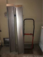Orange metal hand dolly next to two long aluminum ramps