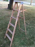 Side perspective of 6-foot wooden step ladder positioned outside, showing A-frame structure, 4 steps and top platform.