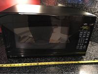 Front view of the black GE Profile microwave showing control panel and digital display.