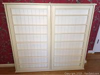 Full front view of the large white wooden wall drying rack with two fold-out panels mounted on a white backing.