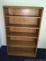 Front view of solid oak bookcase showing five shelves and rounded top edges.