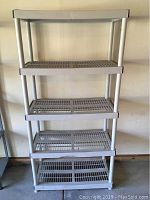Front view of the light gray plastic shelving unit showing five ventilated shelves and four vertical legs.