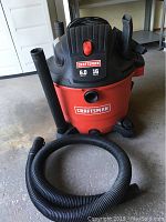 Front view of Craftsman shop vacuum showing brand logos, capacity 16 gallons, power 6.0 peak HP, and a hose mounted to the side.