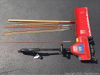 Photo showing Toro Power Shovel Plus, ACE snow shovel, and driveway markers laid on asphalt.