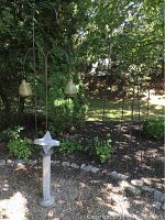 Photo of the shepherd's hooks and the garden sundial together in a garden setting showing the ornate hooks and decorative bee ornaments.