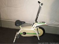 Full side view of the white and green Tunturi exercise bike showing frame, seat, pedals, and handlebars.