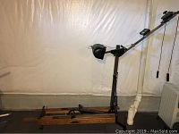 Side view of NordicTrack Achiever rowing machine showing wooden rails, metal frame, and attached rowing handlebar.