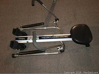 Side view of Whitely RM4 Precision Rowing Machine showing the padded seat, foot pedals with straps, and the frame with branding.