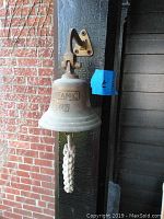 Front view of the Titanic bell showing engraved text and braided pull rope.