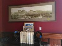 Wide view showing large sepia Mt Washington Hotel photo framed above two smaller color photos, steel bookends, set of books, and ashtray