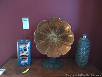 Shows Queen Mary tin, brass gramophone horn, and glass seltzer bottle on wood surface