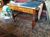 Front angle view of antique wood table showing turned legs and bottom shelf