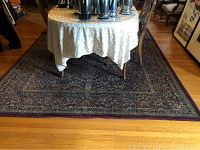Full view of the oriental rug with floral pattern in plum and navy colors under dining table.