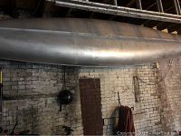 Side view of the 16-foot aluminum canoe hanging from ceiling, showing its full length and condition of the aluminum hull.