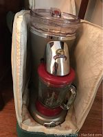 Margaritaville electric margarita machine inside padded carrying case, showing the motor housing, glass blender jar and control knob.
