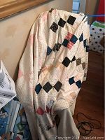 Quilt with white background and multi-color patchwork hung over chair